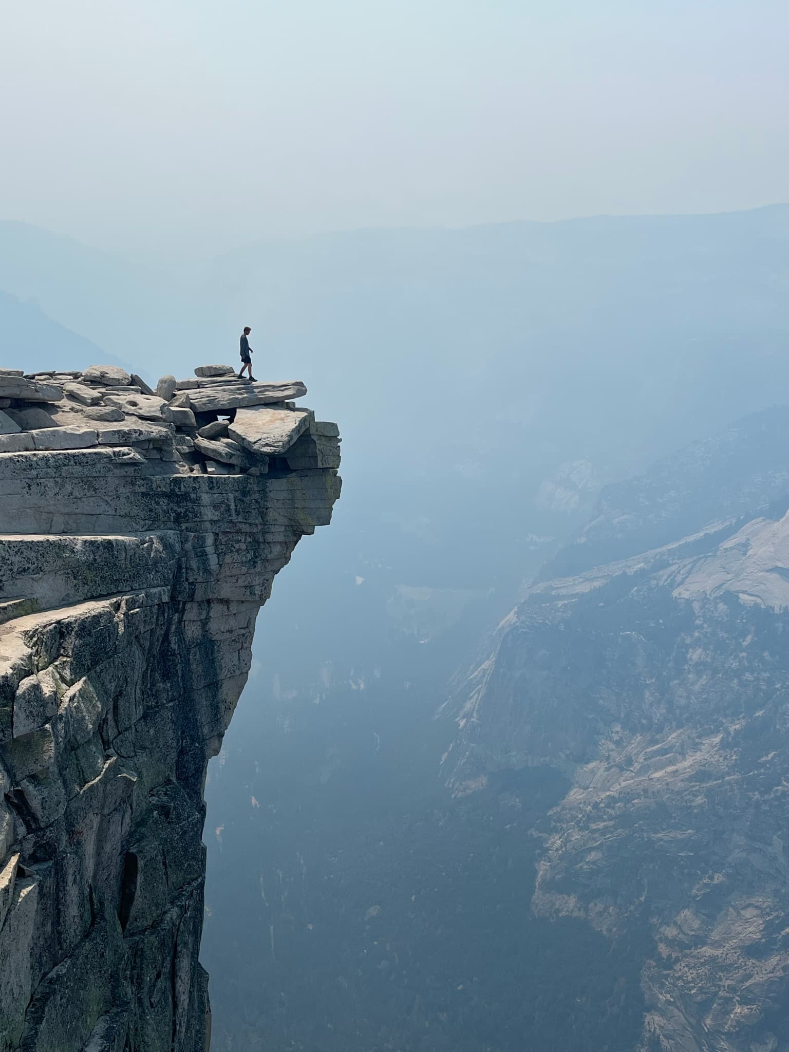 A lone hiker standing at the edge of a sheer granite cliff
