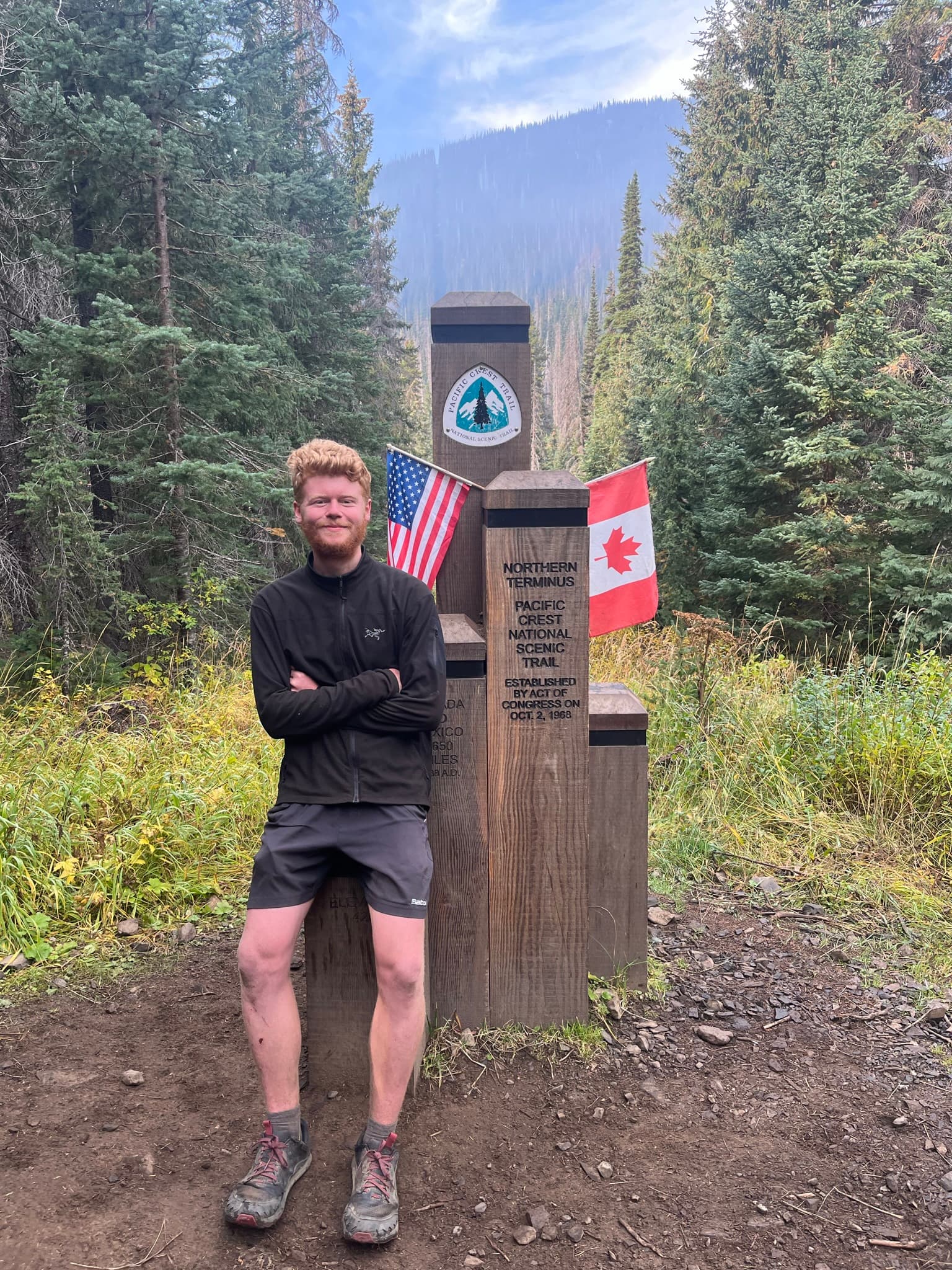 Standing at the northern terminus monument with US and Canada flags